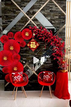 two red chairs sitting next to each other in front of a wall with decorations on it