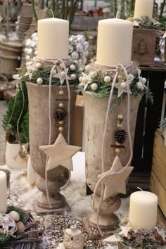 three white candles sitting on top of a table next to christmas decorations and other items