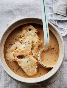 a bowl filled with soup and two spoons on top of a cloth covered table