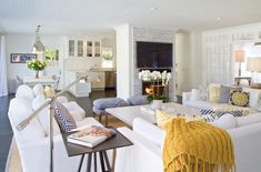 a living room with white couches and yellow throw pillows on the back of them