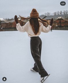 a woman riding skis on top of snow covered ground with lights in the background