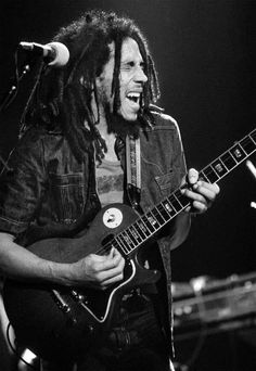 a man with dreadlocks playing an electric guitar