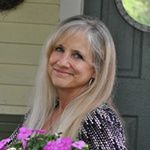 a woman with long blonde hair holding purple flowers