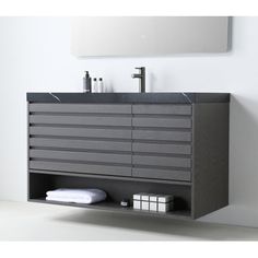 a bathroom vanity with grey drawers and black counter top, along with white towels on the floor