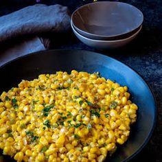 a black plate topped with corn on top of a table