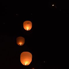 several paper lanterns floating in the air at night