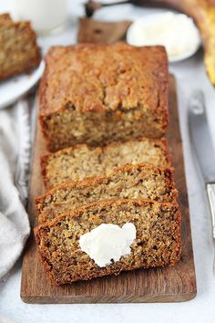 sliced loaf of banana bread on a cutting board with butter and spoons next to it