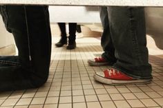 two people standing at a table with their feet on the counter and one person wearing red shoes