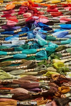 many different colored spools of thread are stacked on top of each other in rows