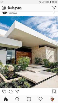 a modern house with plants and rocks in the front yard