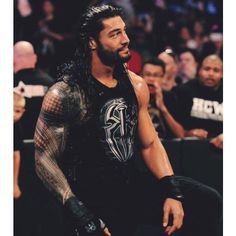 a man with long hair and tattoos standing in front of an audience at a wrestling match