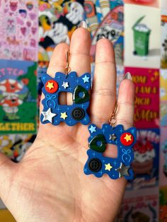 a person is holding two small earrings in front of a wall full of stickers