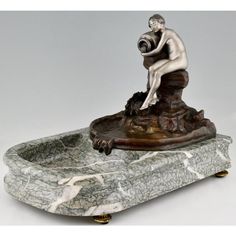 a statue of a man sitting on top of a marble base with a bottle in his mouth