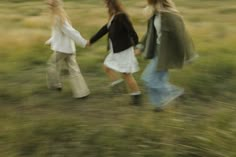 three women walking in the grass holding hands