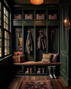 an entryway with green painted walls and lots of storage space, including two coats hanging on the wall