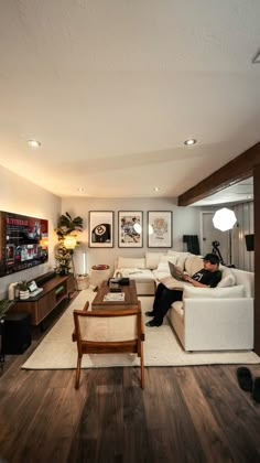 a man sitting on a couch in a living room next to a wooden coffee table