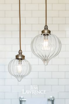 two clear glass pendant lights hanging from a ceiling