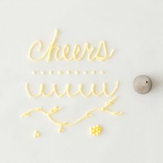 the word cheers is spelled with pasta on a white surface next to a small rock