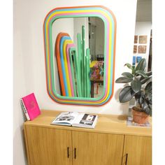 a mirror that is on top of a wooden cabinet next to a potted plant