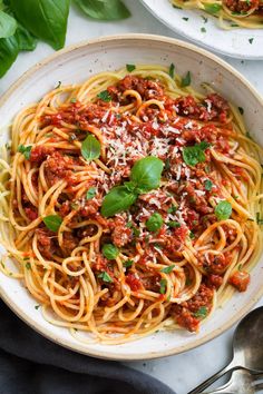 spaghetti with meat sauce and parmesan cheese in a white bowl on a marble table