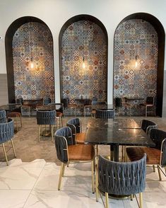 an empty restaurant with chairs and tables in front of decorative wall tiles on the walls