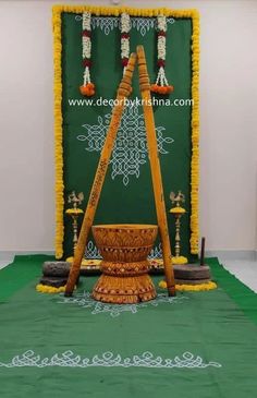 a decorated stage with an ornate wooden stand and green cloth on the floor, surrounded by candles