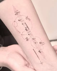 a woman's arm with musical notes on it and an arrow tattoo design in the middle