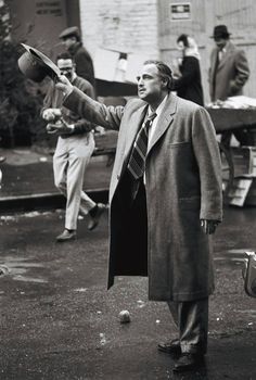 a man in a coat and tie throwing a ball to another man wearing a suit