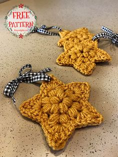 two crocheted star ornaments are sitting on a counter top, one is yellow and the other is brown