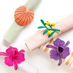 several rolls of fabric with flowers on them and ribbons tied to the ends, all in different colors