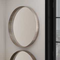 two circular mirrors mounted on the wall next to each other in a room with white walls