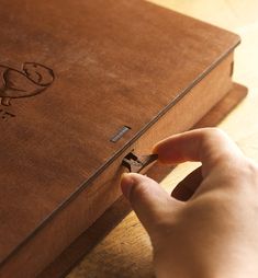 a person is opening the cover of a brown book