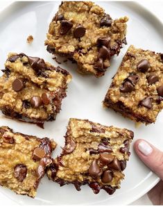 a person holding a plate with four chocolate chip oatmeal bars on it