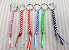 four different colored lanyards on a bed with one keychain in the middle