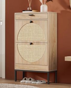 a wooden cabinet with two doors and some shoes on top of it in front of a brown wall