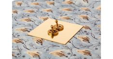 two golden rings on top of a blue floral print table cloth with a gold clip