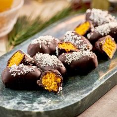 several pieces of chocolate covered with coconut and sprinkles on a green plate