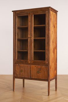 a wooden cabinet sitting on top of a hard wood floor next to a white wall