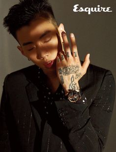 a man with tattoos holding his hand up to his face