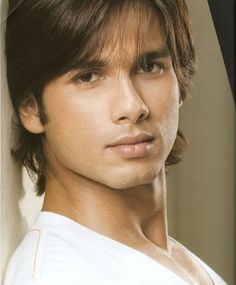 a close up of a young man wearing a white shirt and looking at the camera