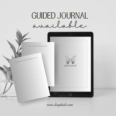 a tablet and notebook with the words guided journal available on it next to a potted plant