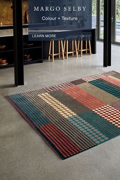 a large area rug is on the floor in front of a sign that reads margo seley colours and texture