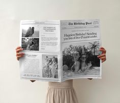 a woman holding up a newspaper with photos on it