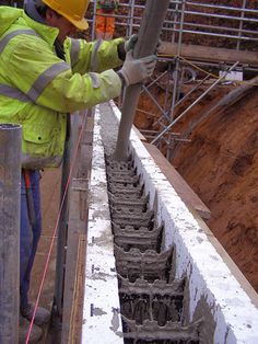 a man in yellow jacket and hard hat working on concrete structure with scaffolding