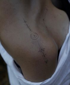 a woman's chest with an arrow tattoo on her left side, and stars in the sky