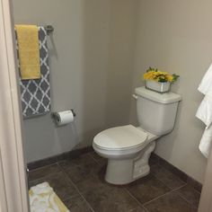 a white toilet sitting inside of a bathroom next to a towel rack and yellow towels