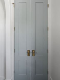 two gray doors with brass handles in a hallway