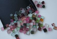 small pieces of glass sitting on top of a white table next to a cell phone