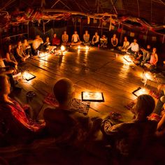 a group of people sitting in a circle on the floor with candles lit around them