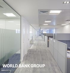 an empty office hallway with glass partitions and white cubicles on both sides, along with the words world bank group